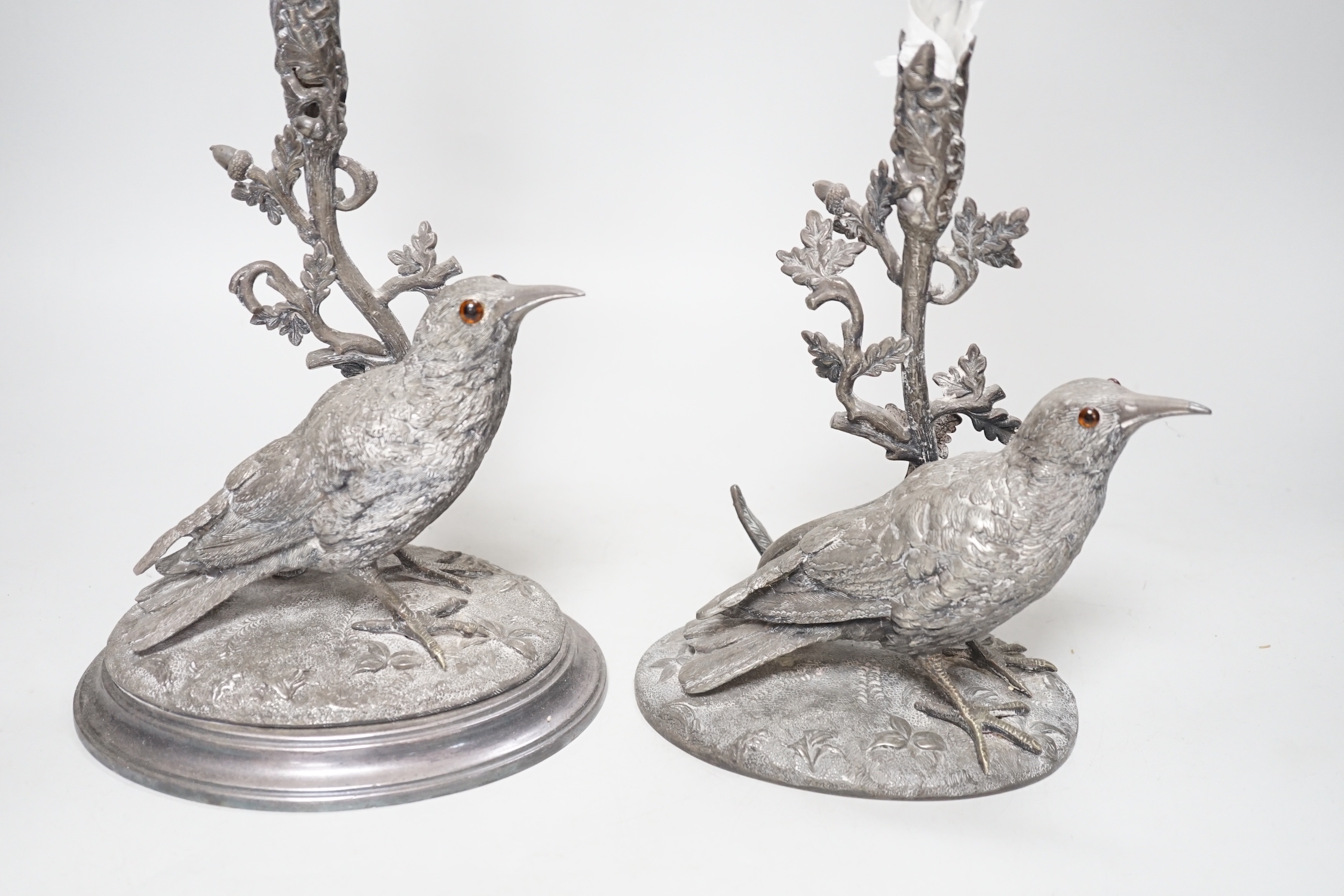 A matched pair of silver plated bird vases, with glass flutes, one with etched decoration, the largest 35cm high